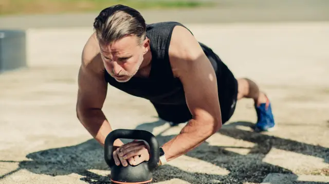 Un hombre realiza ejercicios isométricos en un parque.
