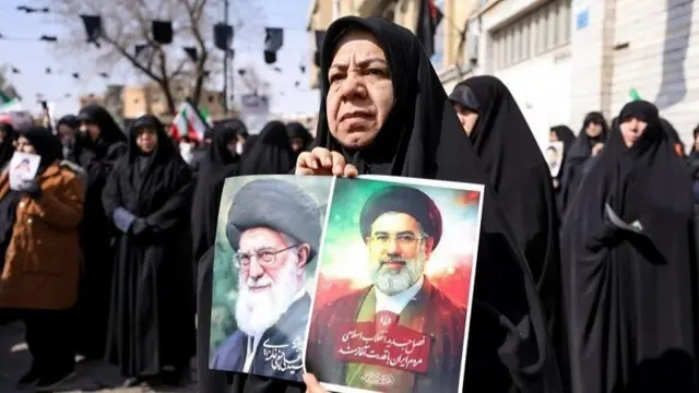 تجمع زنان با چادر مشکی بهعنوان حامیان جمهوری اسلامی ایران، یکی از آنها پوستر خامنهای پدر و پسر را در دست گرفته