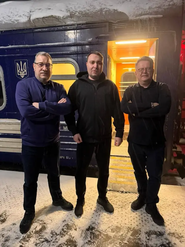 Три мужчины на фоне поезда в снегу