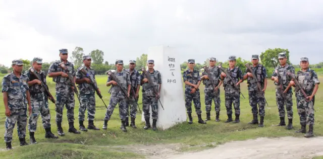 सुनसरीको कोशी गाउँपालिका -१ स्थित नेपाल-भारत सीमा क्षेत्रमा गस्ती गर्दै सशस्त्र प्रहरी। हतियार बोकेका शसस्त्र प्रहरी सीमा स्तम्भमा उभिएर तस्बिर खिचाउँदै।