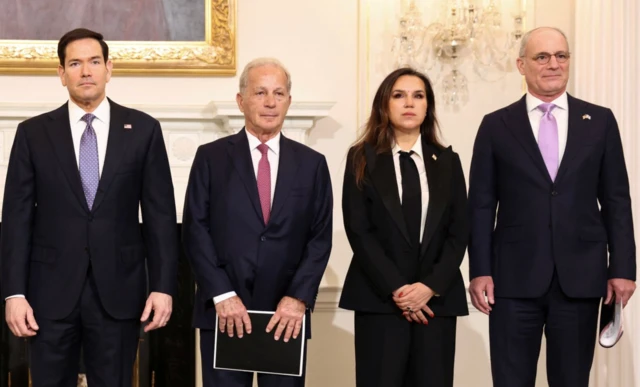 Biri kadın dört resmi giysili yetkili gazetecilere poz veriyor.