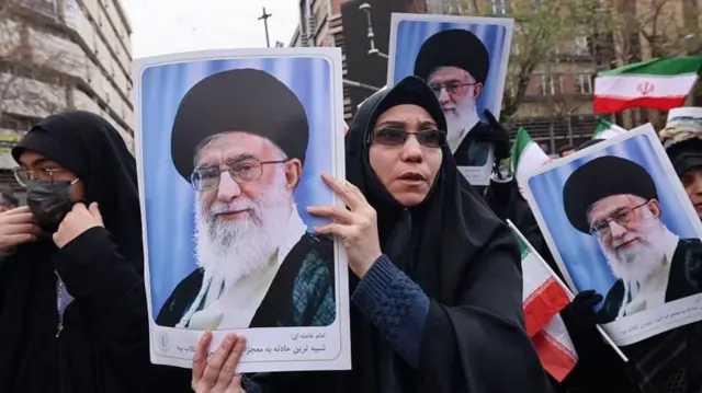 ஜனவரி 14, 2026 அன்று தெஹ்ரானில் நடந்த போராட்டங்களின் போது கொல்லப்பட்ட பாதுகாப்புப் படையினரின் இறுதிச் சடங்கின் போது இரானின் அதிஉயர் தலைவர் அயதுல்லா அலி காமனெயி படங்களை ஏந்தியிருக்கும் இரானிய பெண்கள்.