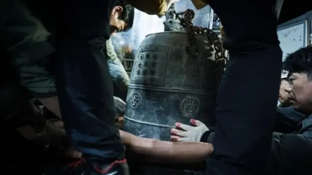 زنی با ناقوس در دست که تلاش دارد این گنجینه تاریخی را از آتش نجات دهد