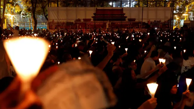 香港维多利亚公园足球场群众在支联会“六四”集会上点燃烛光,主办方在场边防护架上挂起大型北京天安门城楼照片(4/6/2017)
