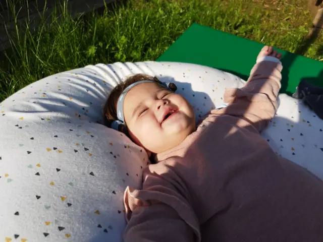 Laia tumbada sobre una almohada en medio del césped.