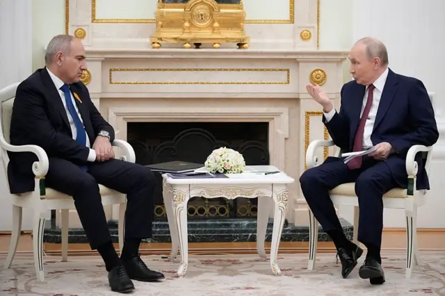 Путин (справа) и Пашинян (слева) сидят по обе стороны камина в Кремле. Путин, жестикулиря, что-то объясняет Пашиняну. Пашинян, сложив руки, смотрит в сторону