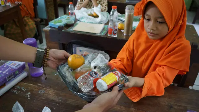 Pelajar menerima kotak makan siang gratis saat simulasi program makan siang gratis di SDN 1 Kepatihan, Kabupaten Jombang, Jawa Timur, Rabu (25/9/2024).