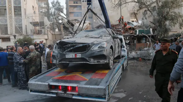 Operarios retiran un vehículo dañado tras el ataque al consulado iraní en Damasco.