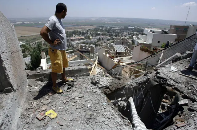 A man surveys the damage of a rocket hitting a building