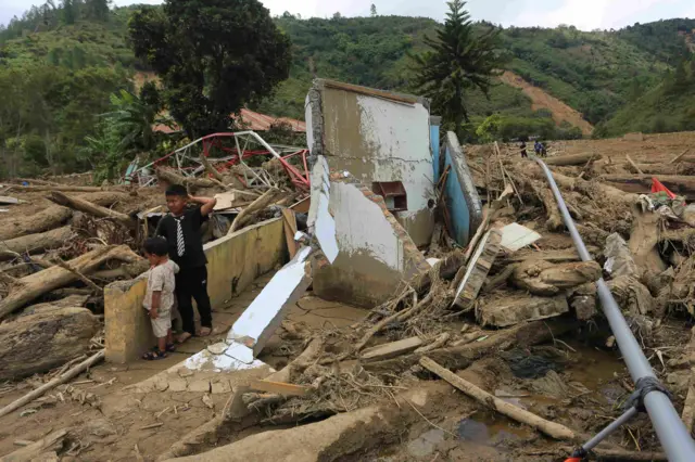 Dua orang anak melihat puing-puing rumahnya yang rusak pasca bencana di Desa Mendale, Kecamatan Kebayakan, Aceh Tengah, Aceh, Jumat (12/12/2025). Data Badan Penanggulangan Bencana Daerah (BPBD) Aceh Tengah menjelaskan dampak bencana hidrometeorologi pada Rabu (26/11) mengakibatkan 234.710 jiwa dari 14 kecamatan terdampak, 34.640 jiwa mengungsi, 24 jiwa korban meninggal dunia dan 8 jiwa korban hilang.