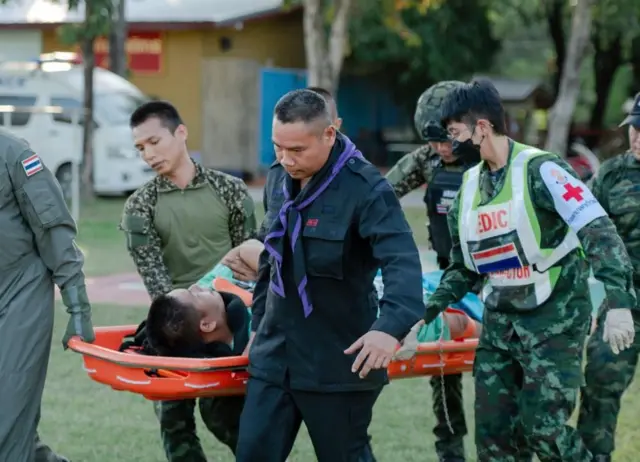 थाई सैनिकहरू स्ट्रेचरमा भएका एक घाइतेलाई बोक्दै