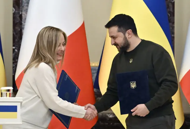 Ukrainian President Volodymyr Zelensky (R) and Italian Prime Minister Giorgia Meloni (L) shake hands before a joint press conference after their meeting in Kyiv on February 21, 2023