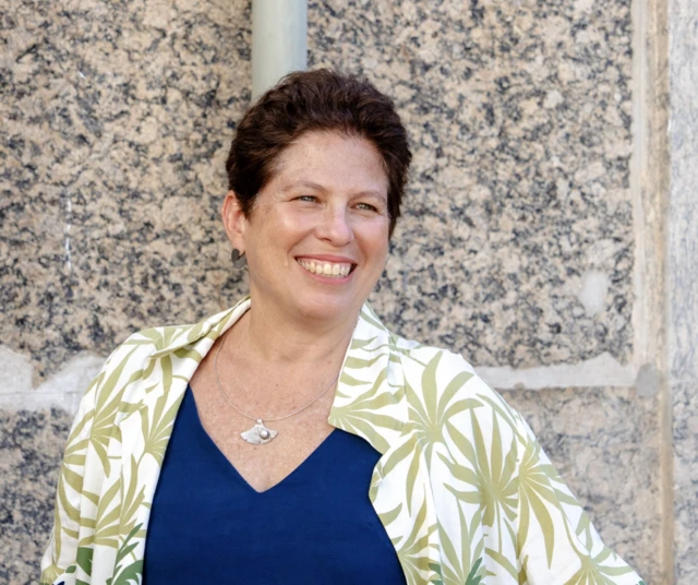 A historiadora Keila Grinberg, com blusa azul e camisa estampada, sorrindo em retrato