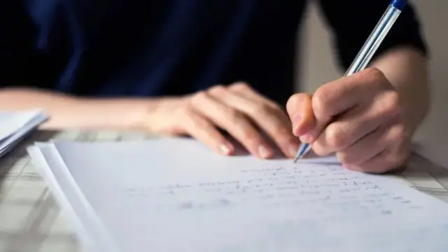 Mão de mulher com caneta escrevendo em caderno