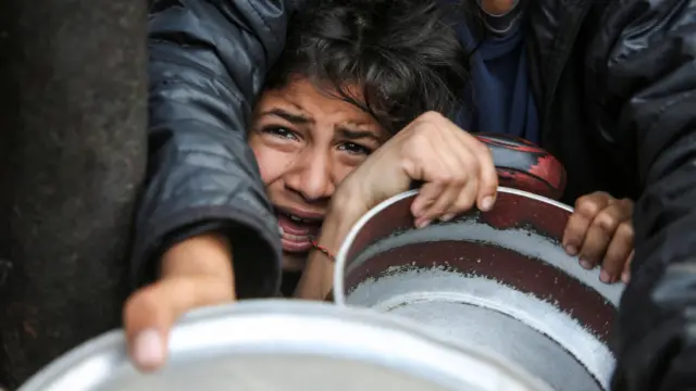 فلسطينيون يتجمعون لتلقي الطعام المطهو في مطبخ خيري في خان يونس جنوب قطاع غزة