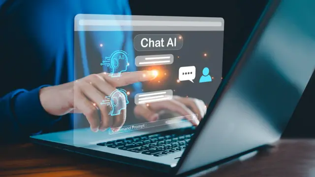 صورة تعبيرية ليد شخص يجري محادثة مع روبوت دردشة يعمل بتكنولوجيا الذكاء الاصطناعي على لابتوب