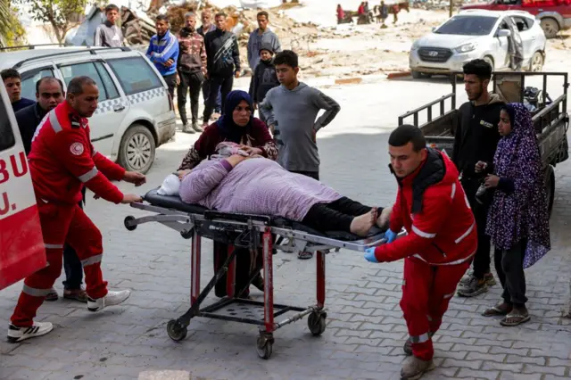 Paramédicos do Crescente Vermelho transportam uma mulher em uma maca


