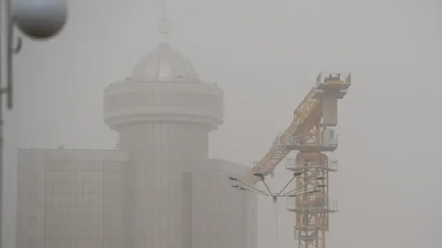 Тошкентда чанг бўронига ўралган банк биноси ва кўтарма кран.