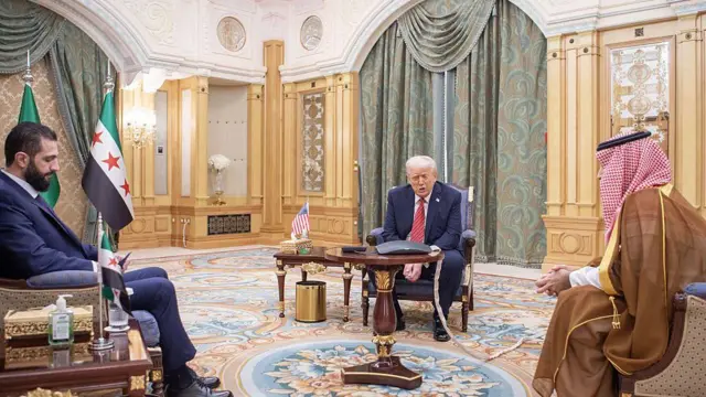 Ахмед аш-Шараа, Дональд Трамп и Мохаммед бин Салман сидят на стульях в роскошном кабинете в Эр-Рияде.
