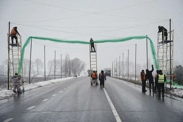 Trabalhadores municipais instalam redes antidrones sobre uma estrada em 28/01/2026, em Kharkiv, Ucrânia