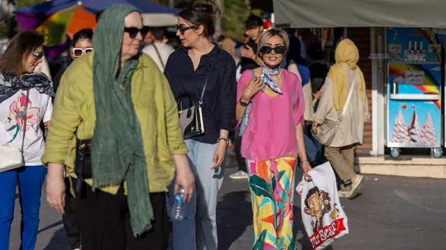 Tahran sokaklarından bir kare, bası yarı kapalı bir kadın ve başı açık dört kadın var. Birinin elinde alışveriş poşeti bulunuyor. 