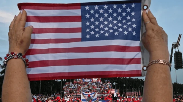 در یک تجمع فردی پرچم آمریکا را بالا گرفته