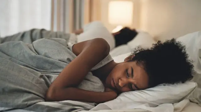 Deux personnes s'allongent pour dormir, dos à dos.