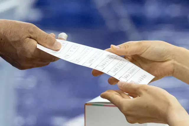 제21대 대통령 선거일인 3일 서울 영등포구 여의도 윤중중학교에 마련된 투표소를 찾은 시민이 투표용지를 받고 있다