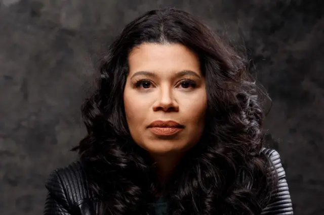 A autora ANa Paula Maia. Ela tem cabelos escuros e ondulados. Veste uma jaqueta de couro preta.