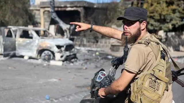 یک نیروی نظامی سوری روی موتور نشسته با دست به جایی اشاره می‌کند