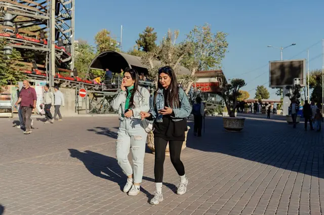 Duas mulheres andando por uma rua em Teerã sem usar o hijab. Uma delas está fumando