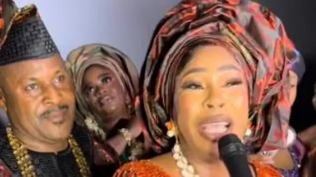 Saidi duro lẹyin Fathia bi obinrin naa ṣe n sọrọ pẹlu ẹrọ gbohungbohun. Obinrin kan wa lẹyin wọn to jẹ alabaaṣe.