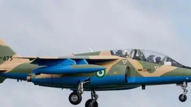 Baalu ologun nla kan, to jẹ alawọ ewe, n fo loju ọrun, awakọ baalu to wọ asọ ologun tii se alawọ ewe wa ninu rẹ.