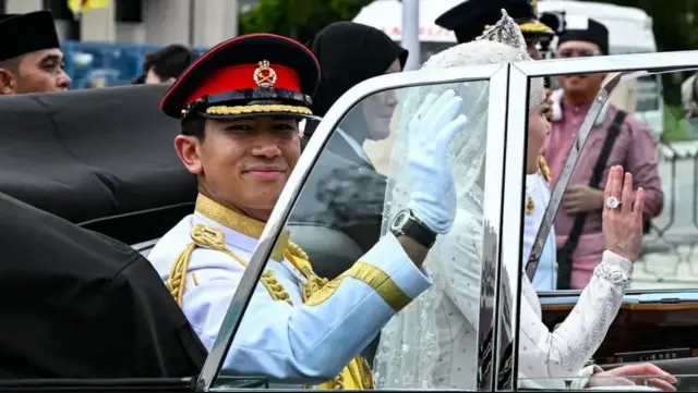 شہزادہ عبدالمتین اور انیشا روسنہ برونائی کے دارالحکومت بندر سیری بیگوان میں اپنی شادی کے جلوس کے دوران عوام کو خوش آمدید کہہ رہے ہیں