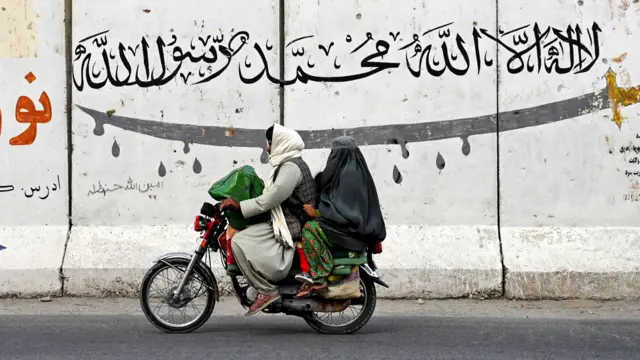 ஆப்கான் ஆண் ஒருவர் பெண் மற்றும் குழந்தையை பைக்கில் அழைத்துச் செல்லும் காட்சி 