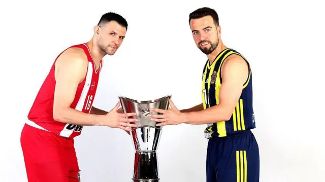 Olympiacos'un kaptanı Kostas Papanikolau ve Fenerbahçe Beko kaptanı Melih Mahmutoğlu, Euroleague kupasına dokunuyor ve karşılıklı olarak kameraya poz veriyor