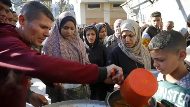 Warga Palestina mengantre untuk mendapatkan makanan dari organisasi bantuan.