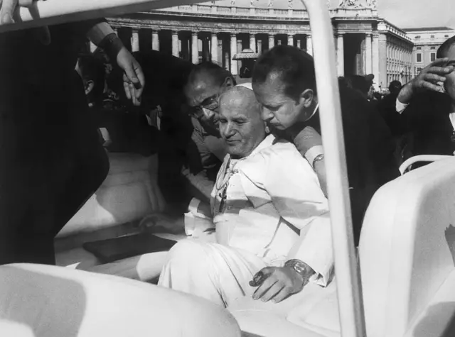 Com sangue nas mãos, o papa João Paulo 2º é socorrido por assessores momentos após ser baleado enquanto andava em seu carro aberto na Praça de São Pedro, em 13 de maio de 1981