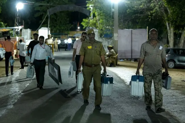 ইভিএম ও ভোটের নানা সরঞ্জাম নিয়ে পোলিং বুথে যাচ্ছেন নির্বাচনকর্মীরা