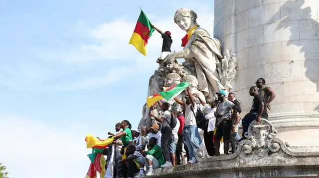 
Des manifestants agitent des drapeaux camerounais lors d'un rassemblement à Paris