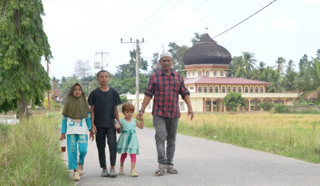 Zaman Huri bersama ketiga anaknya berjalan menuju rumah, usai berziarah.