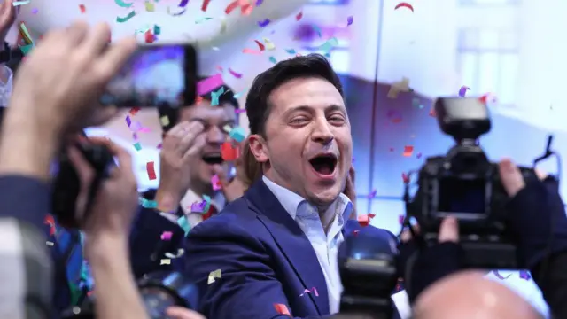 Volodymyr Zelenskiy smiles in a suit while confetti is in the air