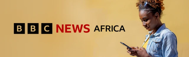 A gefen dama na hoton talla wata mata mai tabarau a kanta, sanye da jaket na denim da rigar T mai launin rawaya tana kallon wayarta. Tambarin BBC News Africa mai baƙi da ja yana gefen hagu na hoton mai bango ruwan zinariya mai laushi.