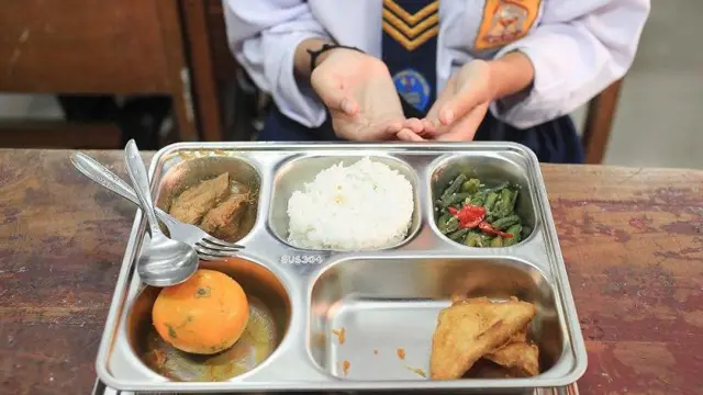 Seorang siswa bersiap menyantap sajian dalam program Makan Bergizi Gratis di SMP Negeri 61, Slipi, Jakarta, Senin (6/1/2025).