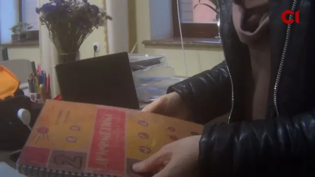 жінка тримає підручник з написом "Арифметика"