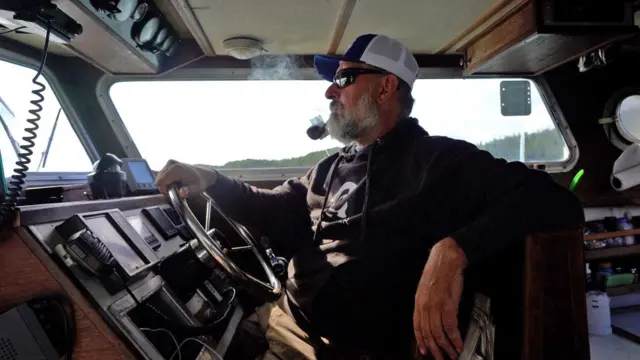 मछली पकड़ने वाली नाव को चलाता हुआ एक मछुआरा