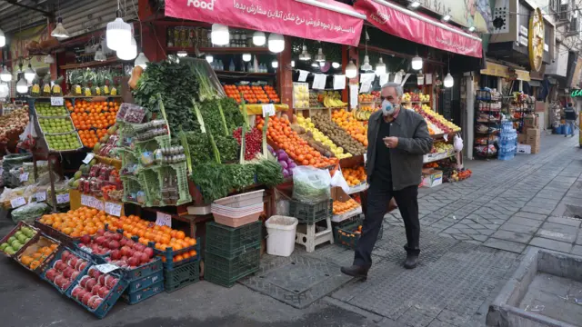 Прохожий в Тегеране около уличного продуктового магазина