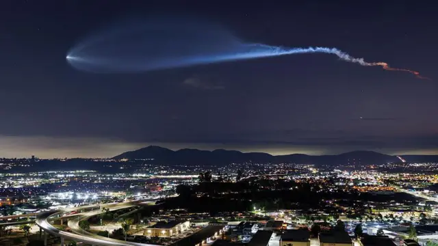 شهری در شب و نور موشک اسپیس ایکس در فضا