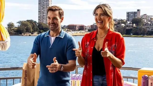 Кадр із серіалу "Сонячні ночі" - чоловік і жінка сміються і показують великі пальці вгору на тлі води