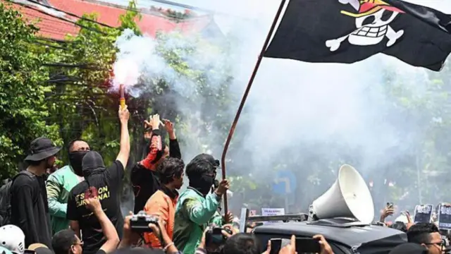 Manifestantes com uma bandeira de caveira